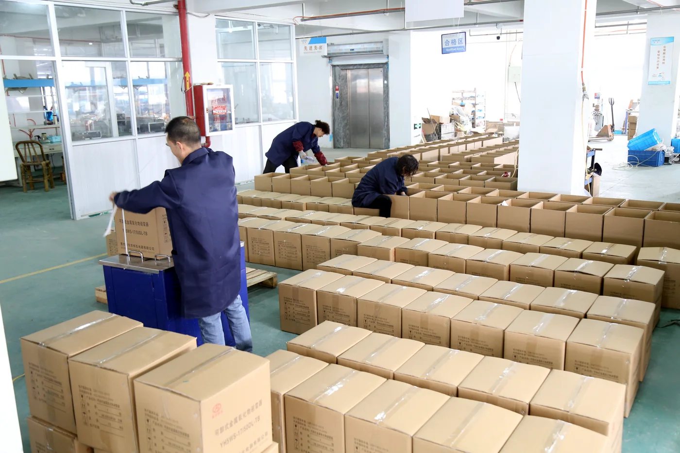 Workers preparing cartons for packaged electrical equipment orders